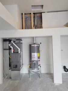 Rheem water heater and high-efficiency furnace installed side by side in a residential utility space.