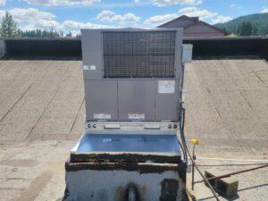 Commercial rooftop HVAC unit installed for efficient heating and cooling, set against a backdrop of clear skies and a rural landscape.