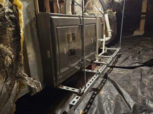 Furnace system installed in a crawl space with secure bracing and ductwork, ensuring efficient heating in a residential home.