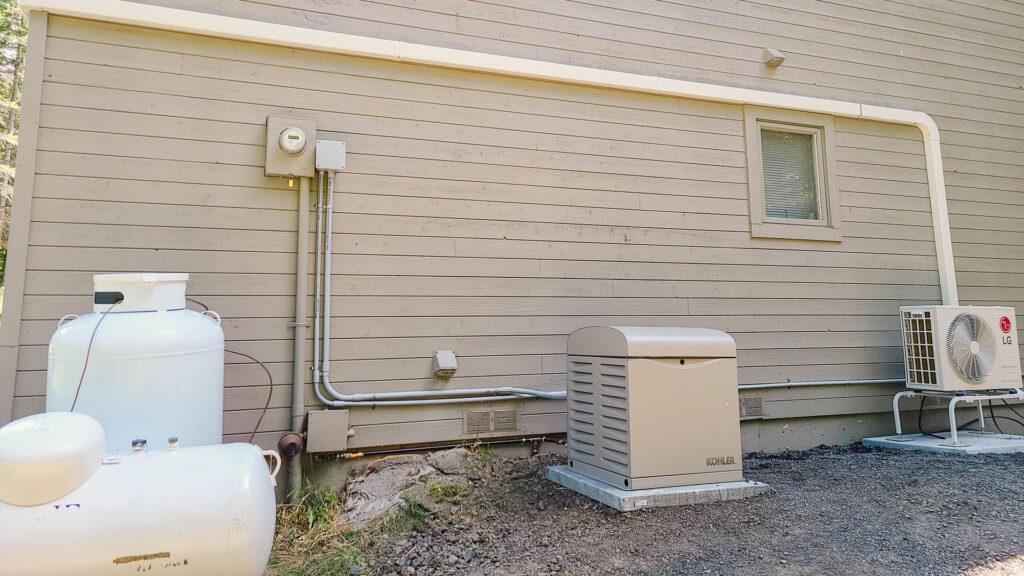 Outdoor HVAC setup with an LG heat pump, propane tank, and Kohler generator, ensuring reliable heating, cooling, and backup power.