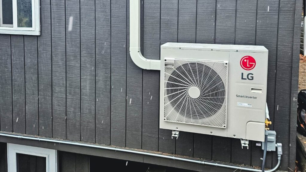 LG Smart Inverter heat pump unit mounted on the exterior of a home with dark wood siding, showcasing energy-efficient HVAC technology.